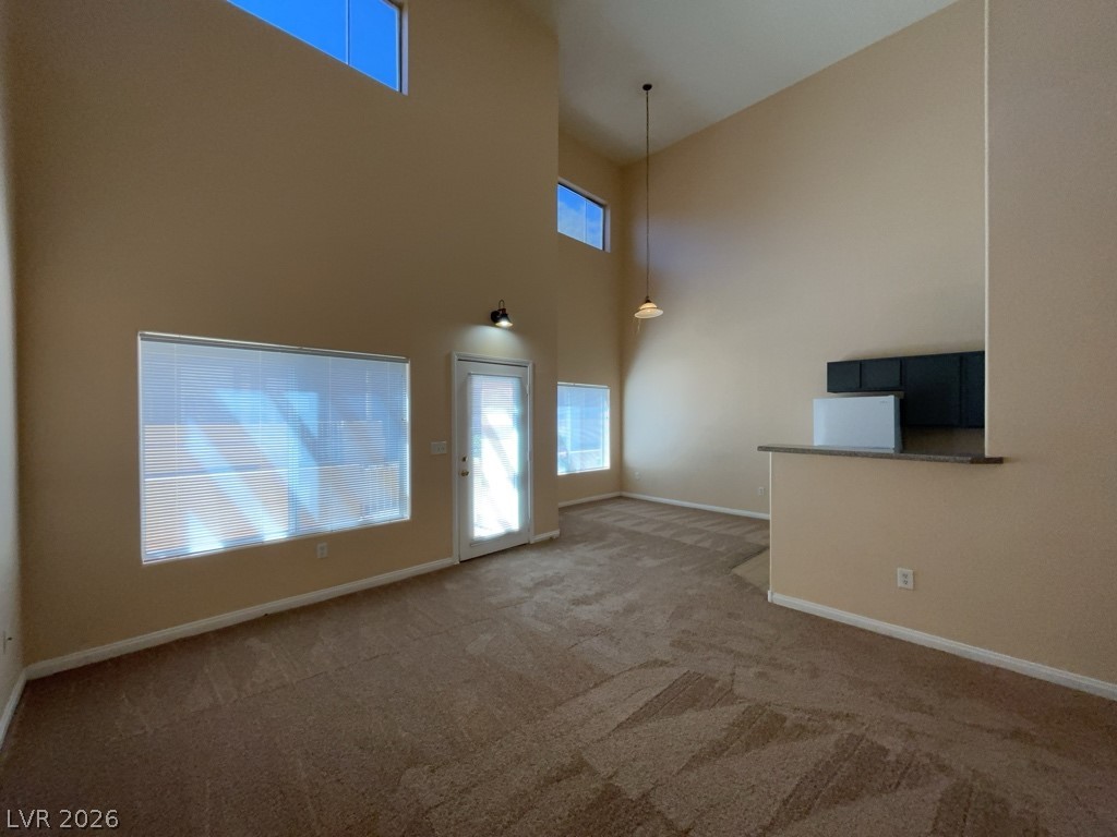 4915 East Russell Road, Unit 145 Las Vegas, NV 89120 - Photo 3 of 13 Unfurnished living room featuring carpet floors and a high ceiling