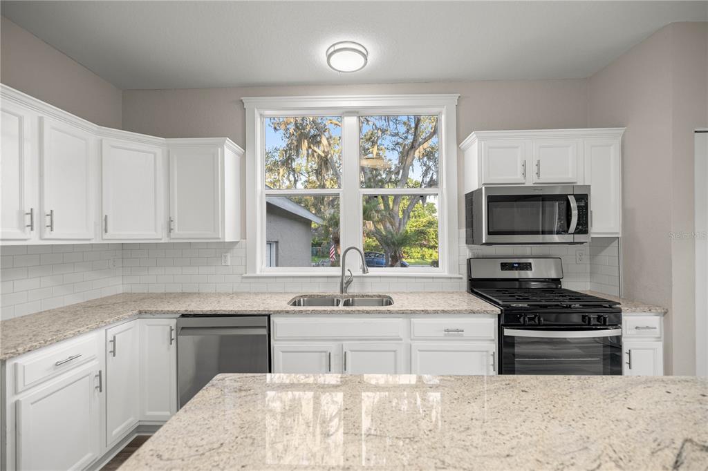 4609 Northeast 7th Street Ocala, FL 34470 - Photo 13 of 36 a kitchen with granite countertop a stove a sink and a microwave