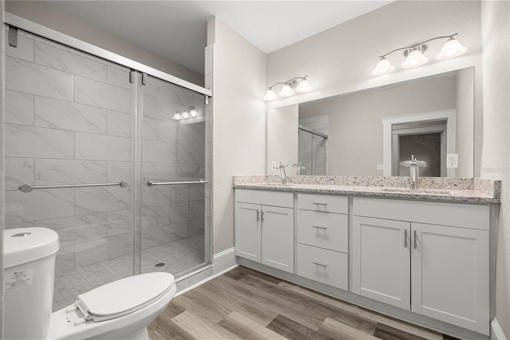 4609 Northeast 7th Street Ocala, FL 34470 - Photo 28 of 36 a bathroom with a granite countertop sink toilet mirror and shower