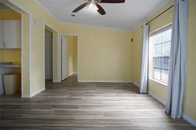 a view of an empty room with window and wooden floor
