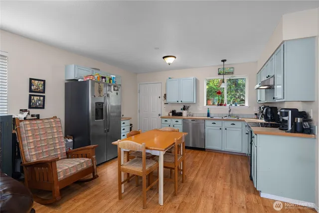 a kitchen with stainless steel appliances a refrigerator a stove a sink dishwasher and a dining table with wooden floor