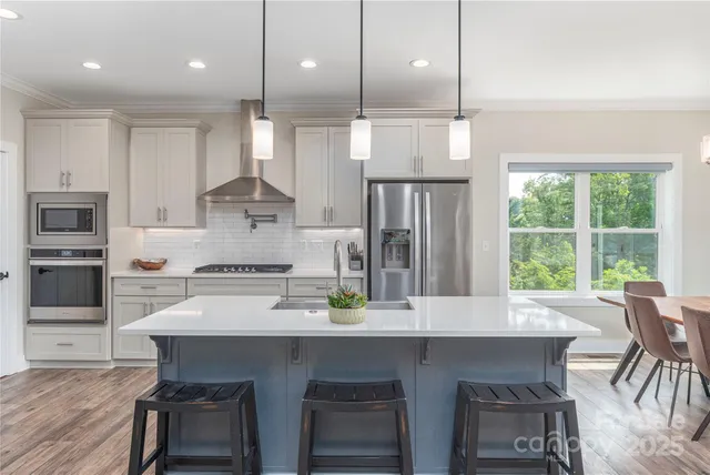 a kitchen with stainless steel appliances a dining table chairs stove and refrigerator