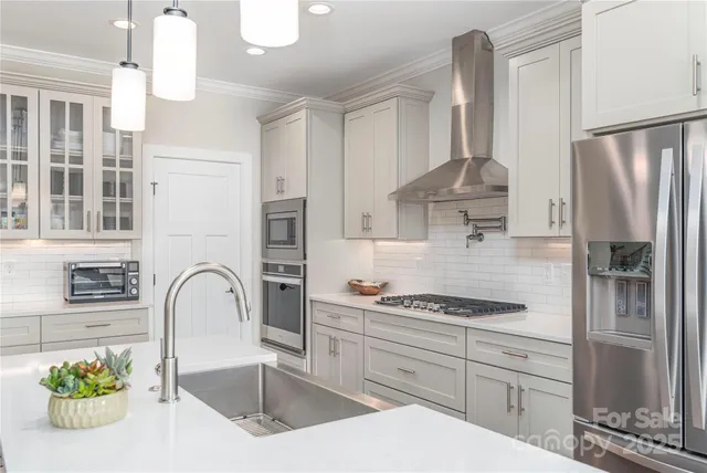a kitchen with stainless steel appliances granite countertop a refrigerator a sink a stove and white cabinets