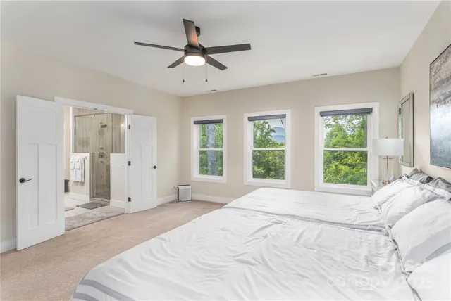a spacious bedroom with a large bed a chandelier and windows