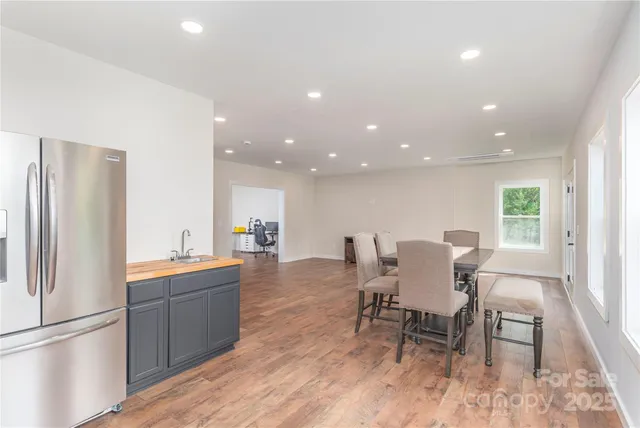 a kitchen with stainless steel appliances a dining table chairs and a refrigerator