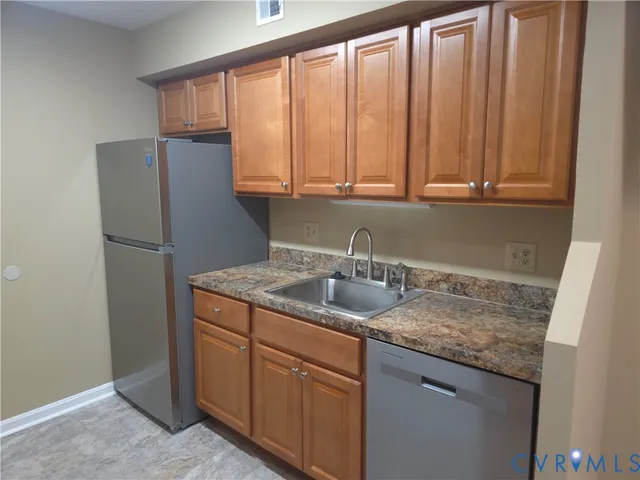 a kitchen with stainless steel appliances granite countertop a sink and a refrigerator