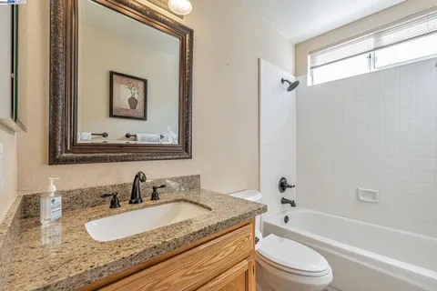 a bathroom with a granite countertop sink toilet and a mirror