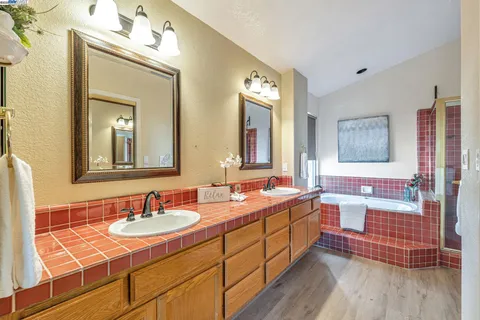 a bathroom with a double vanity sink mirror and bathtub