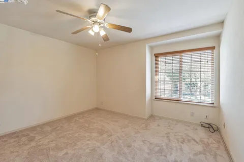 an empty room with windows and fan