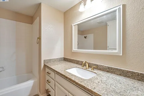 a bathroom with a granite countertop tub sink and mirror