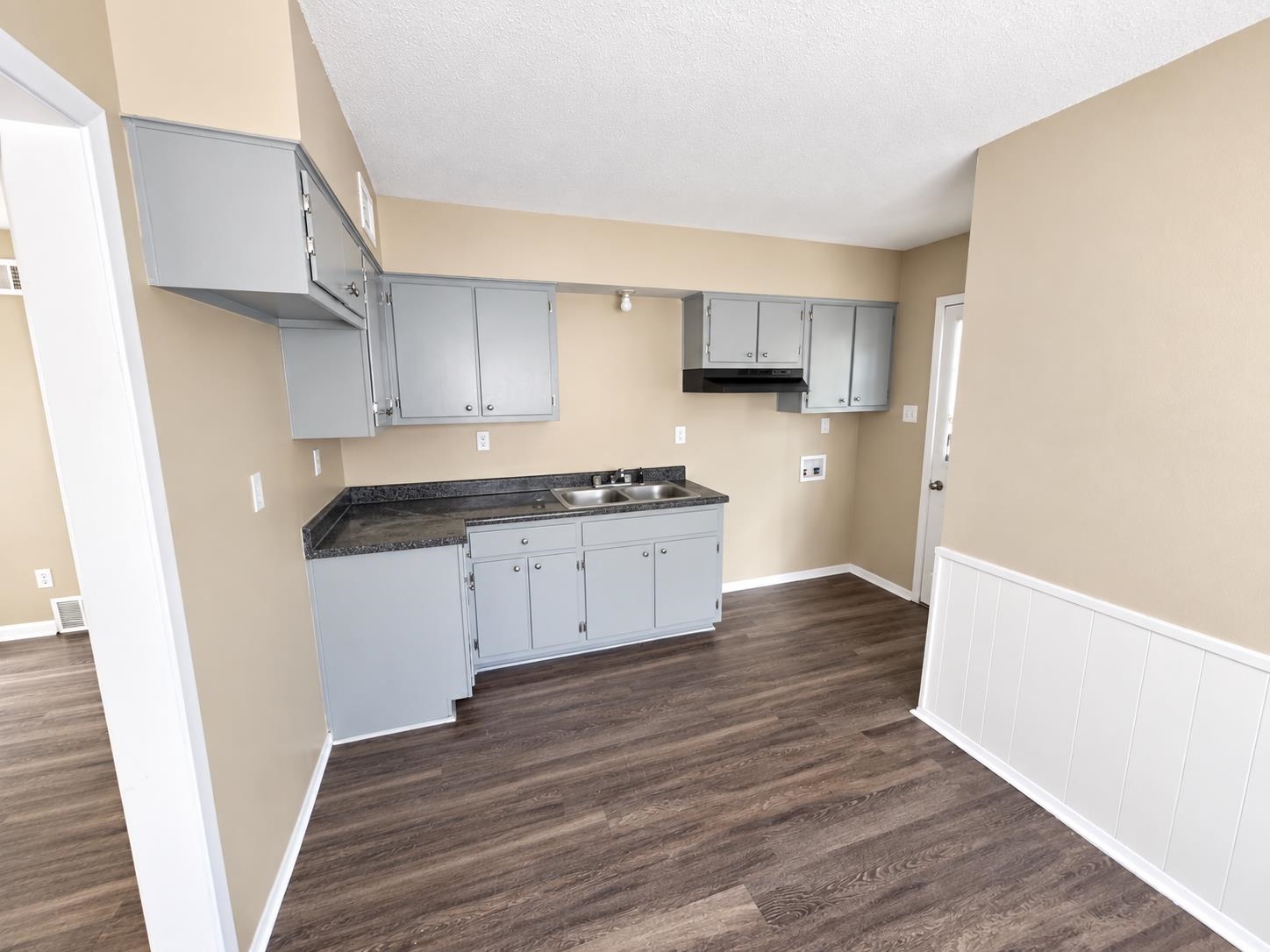 630 Blackhawk Road Memphis, TN 38109 - Photo 10 of 14 Galley kitchen featuring wood-finish flooring, two-tone cabinetry, a dual-basin sink, and a built-in range hood