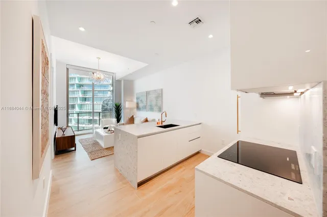 a kitchen with a sink a counter and a living room view