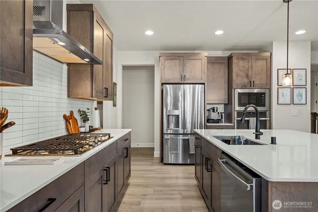 a kitchen with kitchen island stainless steel appliances a sink stove refrigerator and cabinets