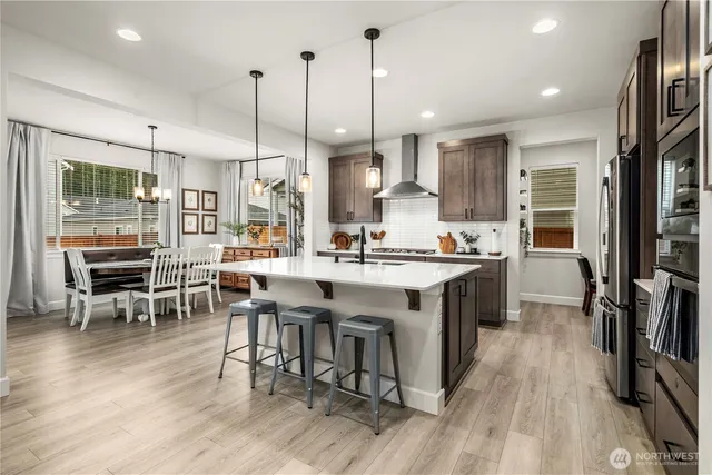 a kitchen with stainless steel appliances granite countertop dining table chairs stove a refrigerator and cabinets