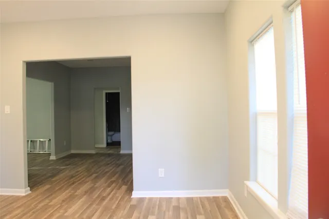 a view of a hallway with wooden floor and a bathroom