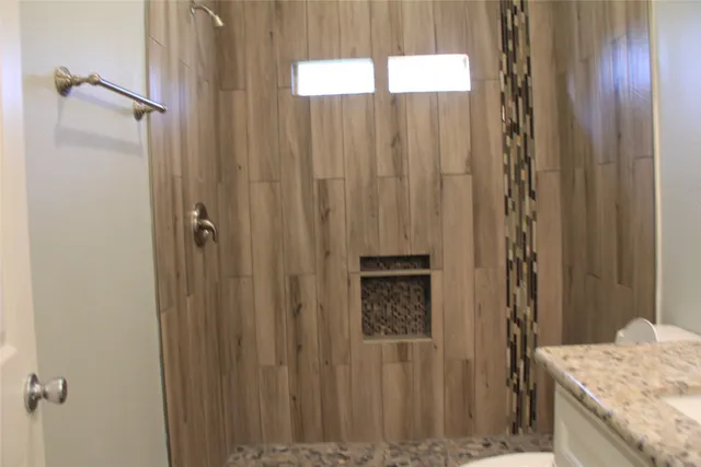 a bathroom with a granite countertop shower and a sink
