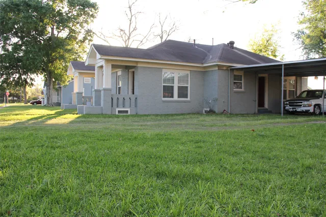 a view of a yard in front of a house with large tree