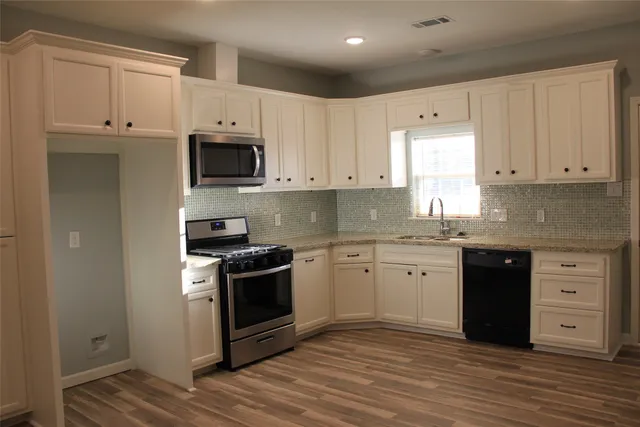 a kitchen with granite countertop white cabinets and stainless steel appliances