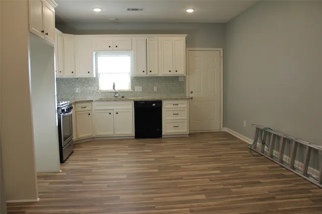a large kitchen with granite countertop a sink and cabinets
