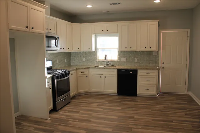 a kitchen with stainless steel appliances granite countertop a stove a sink and a refrigerator