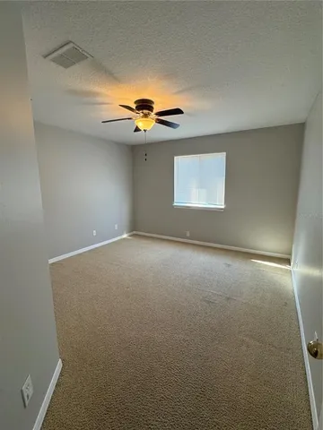 an empty room with a ceiling fan and a window
