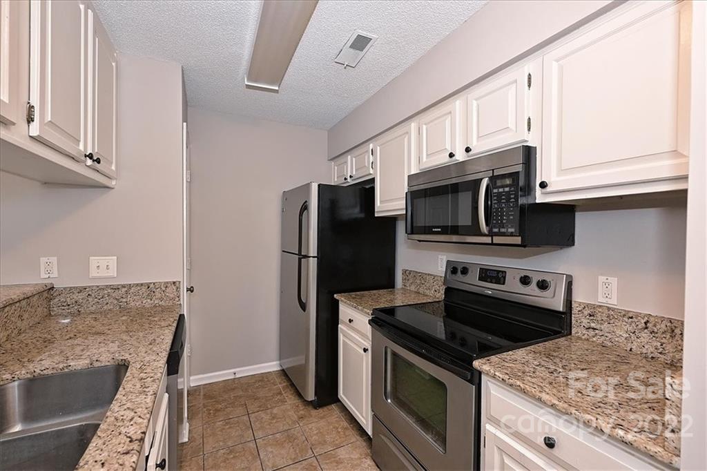 226 Queens Road, Unit 78 Charlotte, NC 28204 - Photo 11 of 32 a kitchen with stainless steel appliances granite countertop a stove microwave and refrigerator