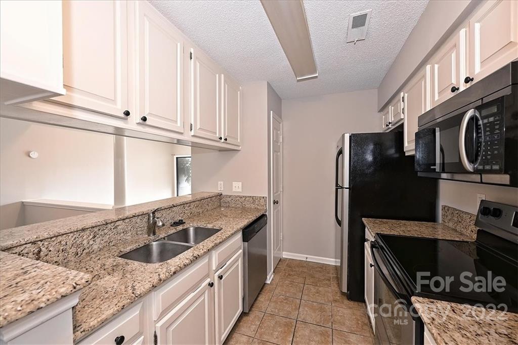 226 Queens Road, Unit 78 Charlotte, NC 28204 - Photo 13 of 32 a kitchen with stainless steel appliances granite countertop a sink stove and refrigerator