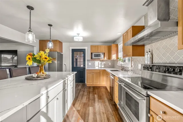 a kitchen with stainless steel appliances granite countertop a sink a stove top oven a counter space and cabinets