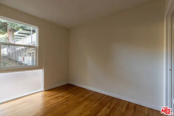 a view of an empty room with wooden floor and closet