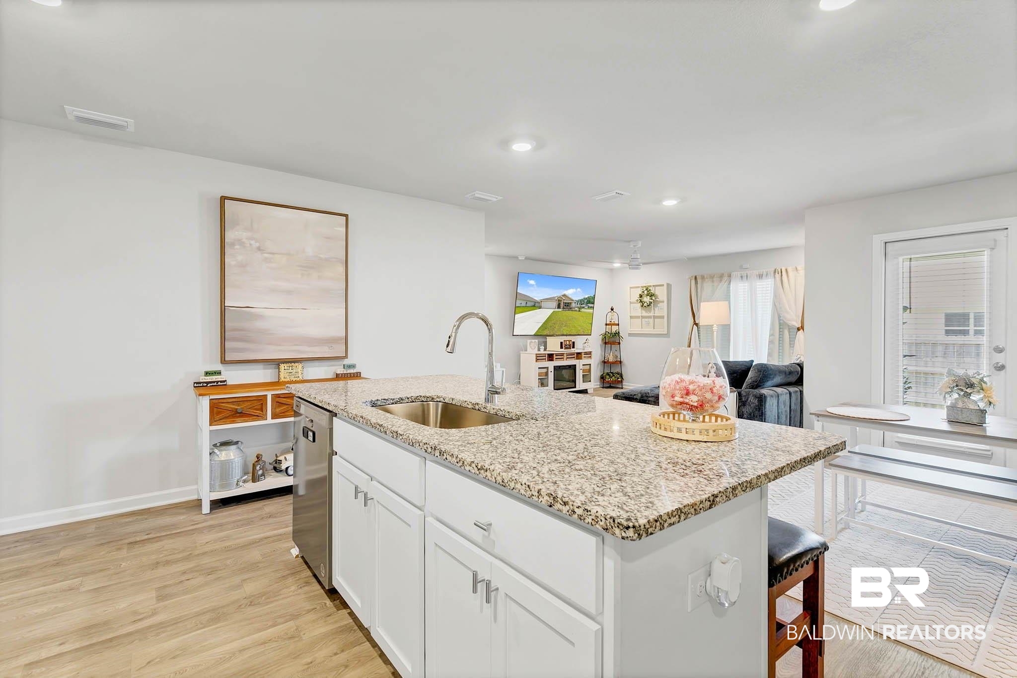 17217 REFLECTION Street Loxley, AL 36551 - Photo 14 of 83 Kitchen with stainless steel dishwasher, white cabinetry, light stone countertops, light wood-style flooring, and a center island with sink