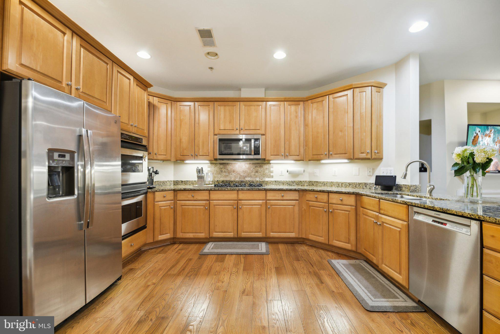 47753 Ramshead Terrace Sterling, VA 20165 - Photo 8 of 37 a kitchen with stainless steel appliances granite countertop a refrigerator a sink dishwasher a stove with wooden cabinets and floor