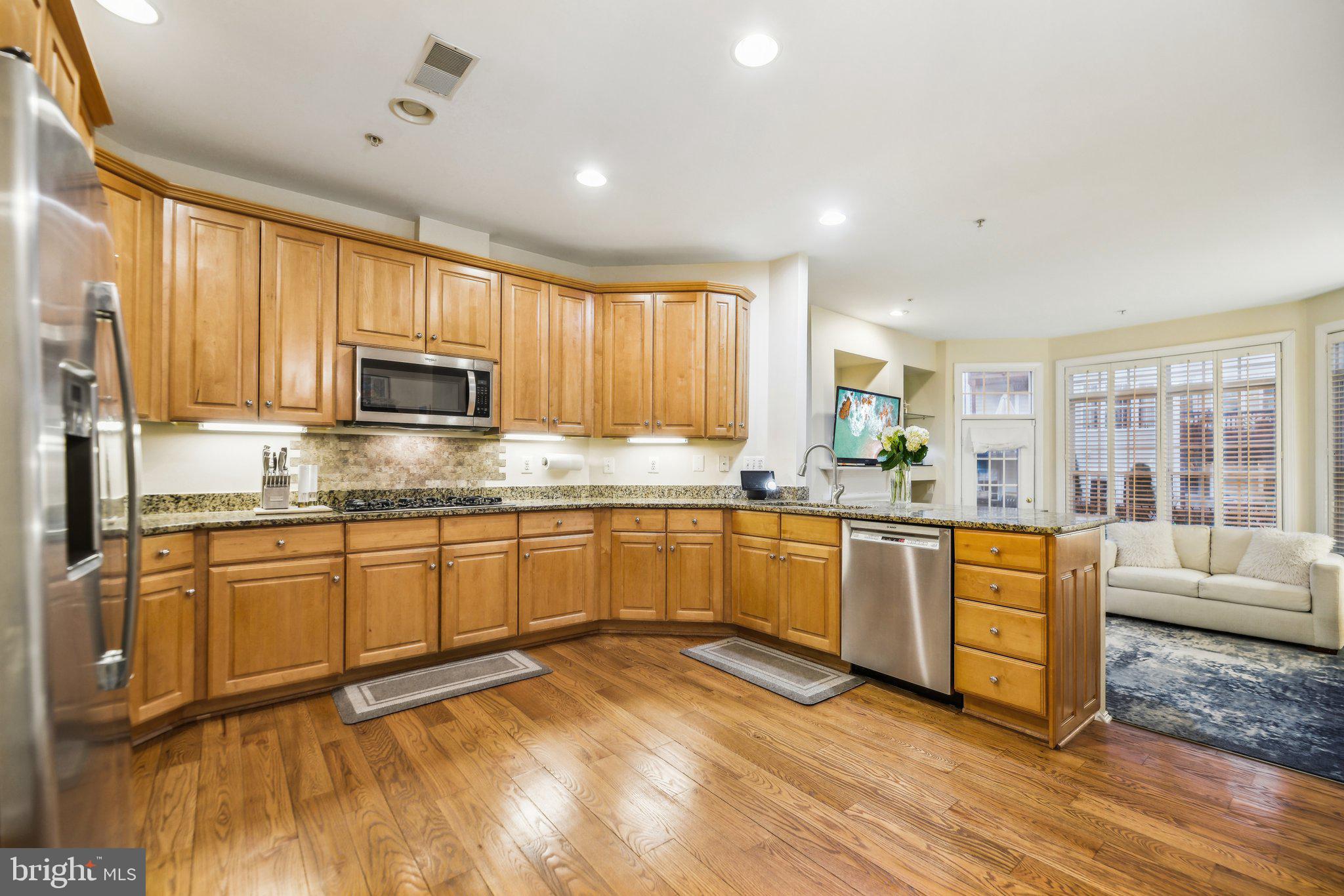 47753 Ramshead Terrace Sterling, VA 20165 - Photo 9 of 37 a kitchen with stainless steel appliances granite countertop wooden cabinets a stove a sink and dishwasher with wooden floor