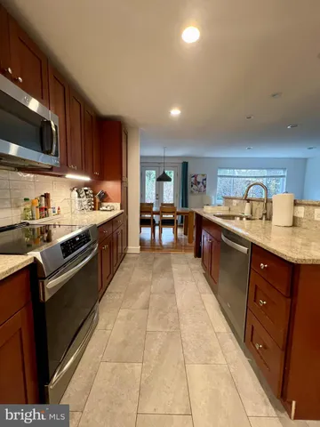 a large kitchen with stainless steel appliances granite countertop a sink and cabinets