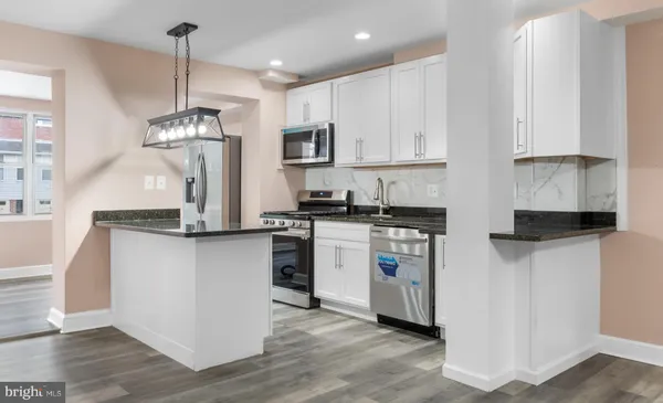 a kitchen with stainless steel appliances granite countertop a refrigerator a sink dishwasher a stove and white cabinets with wooden floor