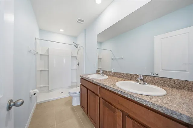 a bathroom with a granite countertop sink shower mirror and toilet
