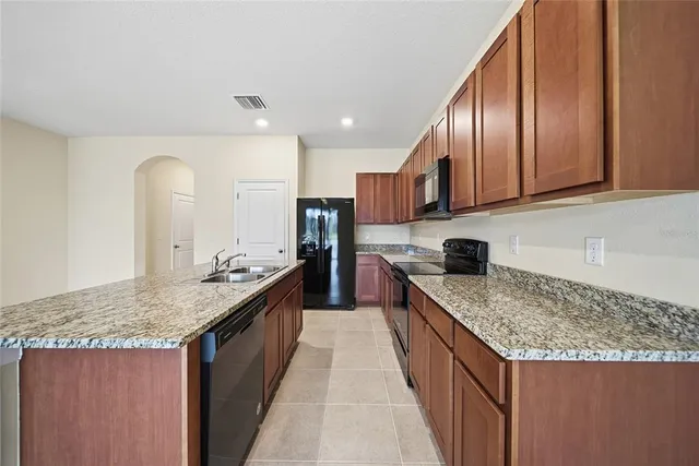 a kitchen with granite countertop kitchen island stainless steel appliances granite countertop sink stove top oven and cabinets