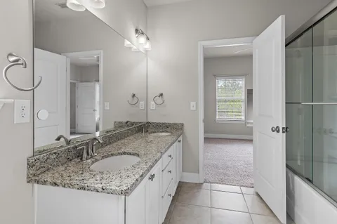 a bathroom with a granite countertop double vanity sink and a mirror