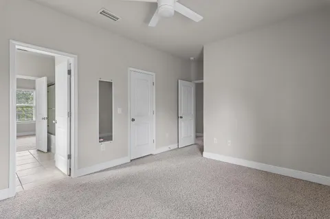 an empty room with an entryway and chandelier fan