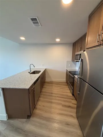 a kitchen with stainless steel appliances a refrigerator and a wooden floor