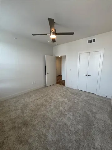 an empty room with staircase and ceiling fan