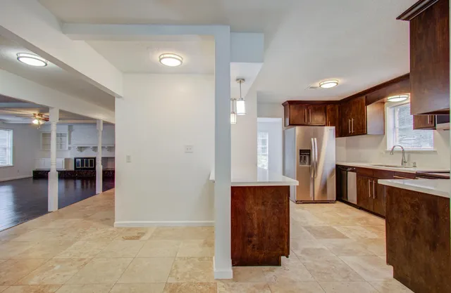 a kitchen with stainless steel appliances kitchen island granite countertop a refrigerator and a sink
