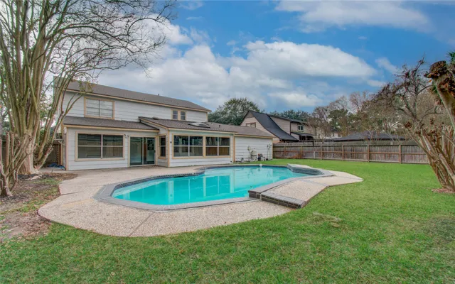 a view of house with swimming pool and yard