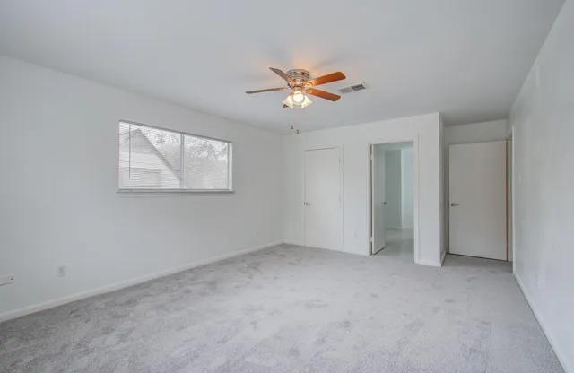 a view of an empty room with a ceiling fan and a window