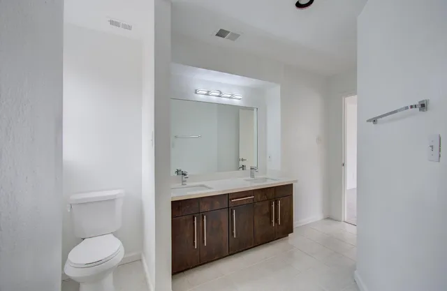 a spacious bathroom with a toilet a sink a mirror and vanity
