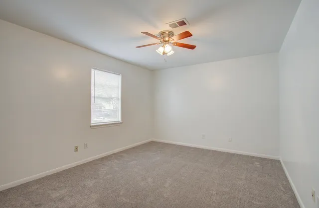 an empty room with a window and a ceiling fan