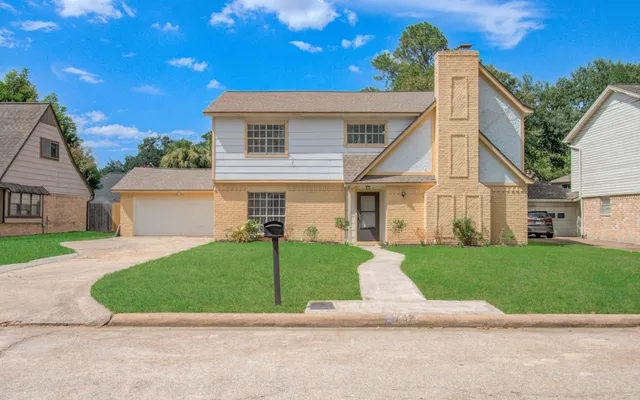 a view of a white house next to a yard with big trees