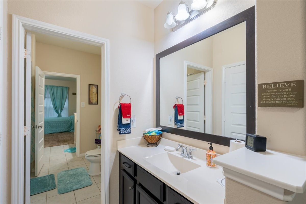 22002 Flashing Ridge Spring, TX 77389 - Photo 28 of 43 This photo showcases a bright bathroom with a large mirror, modern fixtures, and ample counter space. The bathroom connects to a bedroom with teal accents, creating a cohesive, inviting space.