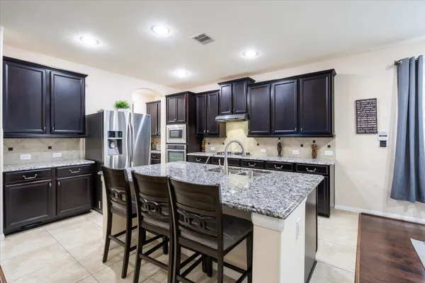 a kitchen with stainless steel appliances granite countertop wooden cabinets a stove top oven a sink and dishwasher