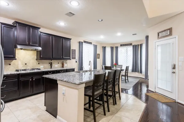 a kitchen with granite countertop stainless steel appliances a stove a sink a microwave a dining table and chairs