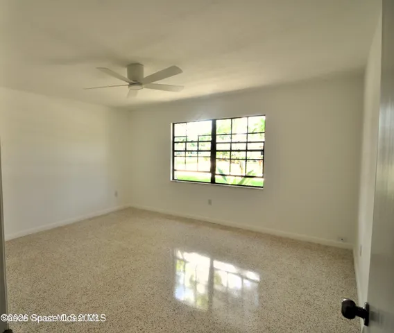 an empty room with windows and fan